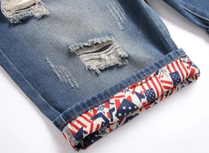 Dettaglio di pantaloncini di jeans con strappi e fodera con bandiera sull'orlo risvoltato