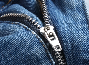 Detailed macro view of high-quality silver metal zipper on classic blue denim shorts