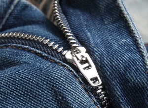 Detailed close-up of heavy-duty metal zipper on slim fit distressed blue denim shorts