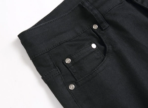 Detailed macro view of black denim fabric with silver metal rivets and jeans engraving