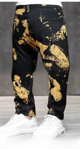 Detailed close-up of men's slim fit jeans with artistic gold splatter print on black denim