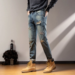 Detailed view of men's distressed blue denim jeans with vintage wash and ripped patterns