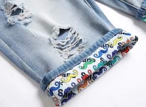 Detail showing distressed denim fabric with ripped holes and unique patterned folded hem