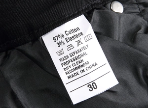 Gros plan de l'étiquette de lavage d'un jean noir avec 97% coton et la taille 30