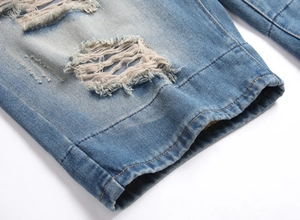 Détail macro du short en jean pour homme montrant les déchirures et la texture du tissu