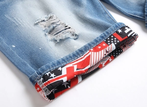 Detail of light blue distressed denim shorts featuring ripped holes and star flag cuff pattern