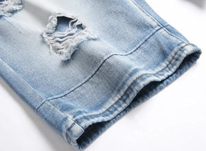 Detail of light blue denim shorts featuring distressed holes and reinforced stitched hems