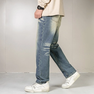 Close-up of vintage blue wash denim jeans with faded whiskered texture and straight cut