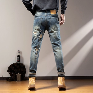 Detail of slim-fit retro wash denim with lightning embroidery and star patches