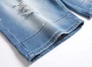 Close-up of light blue washed denim shorts with distressed ripped holes and fringe details