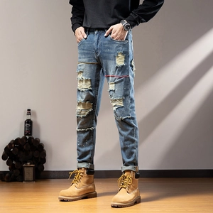 Detail of distressed men's denim with paint splatter and ripped patchwork on slim fit jeans