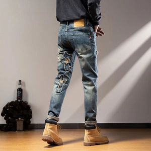 Close-up of star patch embroidery and distressed details on blue denim jeans for men