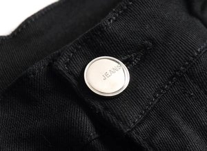 Vue détaillée d'un bouton de jean en métal argenté sur un tissu en denim noir