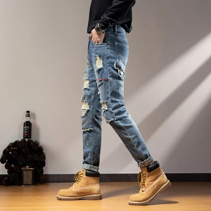 Slim fit men's distressed blue jeans with heavy ripped details and white paint splatters