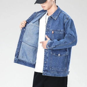 Detailed view of mid-blue washed denim jacket with utility pockets and metal buttons