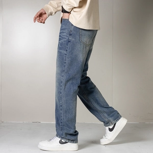 Détail d'un jean bleu droit pour homme avec délavage moustaches et style classique cinq poches