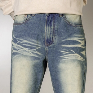Close-up of vintage blue straight jeans with heavy whiskering and washed denim texture