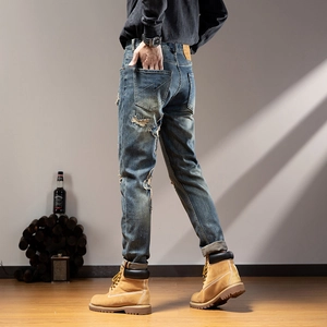 Close-up of distressed blue denim jeans showing ripped details and back pocket embroidery
