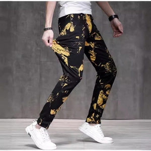 Men's slim fit black jeans featuring a bold golden graffiti print and stretch fabric