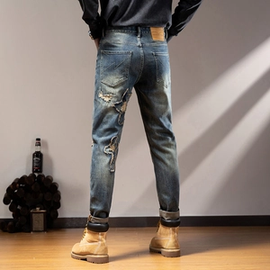 Rear view of distressed men's denim jeans with star patch and vintage wash detailing
