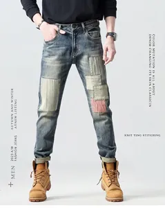 Detail of vintage blue slim fit jeans featuring creative patchwork and striped fabric inserts