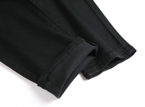 Détail de la couture de l'ourlet et texture sergé sur le jean noir ajusté pour hommes
