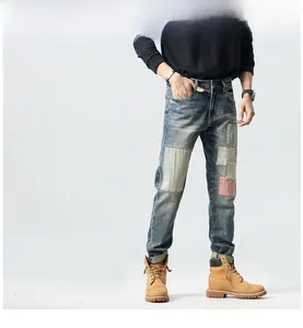 Detailed shot of men's slim fit jeans with red and white striped patchwork and wash details