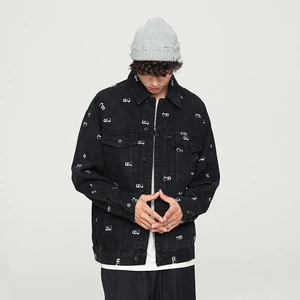 Macro view showing the white embroidered symbols and texture on the black denim jacket