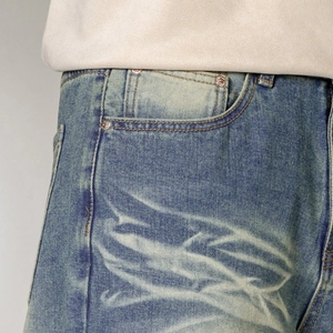 Close-up of vintage blue denim jeans featuring white gradient totem pattern on the front pocket