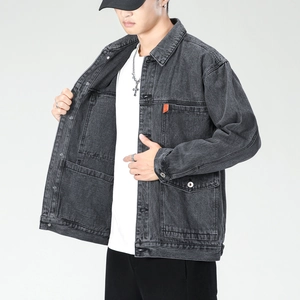 Close-up of charcoal gray denim jacket featuring utility pockets and orange woven label