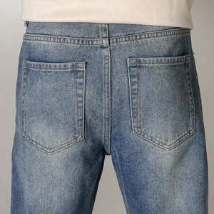 Détail des poches arrière d'un jean bleu avec coutures contrastées et effet délavé