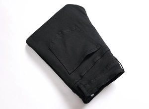 Détail de la texture du denim noir et des coutures de la poche arrière du jean slim pour homme