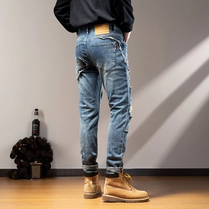Detail view of men's slim ripped jeans with leather patch and white paint splatter design