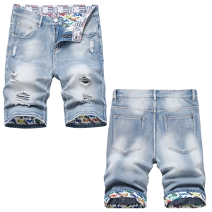 Men's light blue distressed denim shorts with vintage ripped holes and graffiti lining