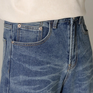 Gros plan sur un jean bleu délavé avec poches incurvées et rivets métalliques dorés