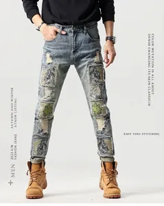 Dettaglio jeans azzurri strappati con ricamo a palma e toppe decorative stile vintage
