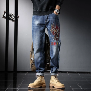 Détail de la broderie de dragon sur un jean en denim bleu foncé délavé pour homme