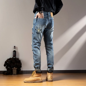 Detail of distressed ripped denim jeans featuring vintage frayed edges and side pleats