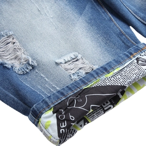Men's slim-fit ripped denim shorts in light blue with unique newspaper print cuff detail