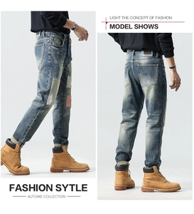 Detail of slim fit patchwork jeans with vintage wash and distressed fabric patches