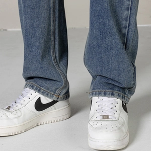 Détail du jean droit bleu pour hommes montrant la texture sergée et l'ourlet plissé