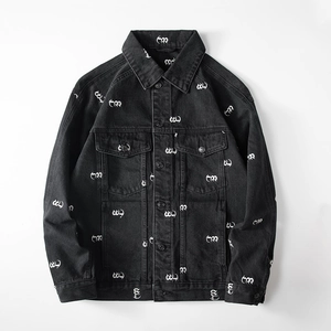 Detail of black denim jacket featuring white all-over logo print and metal buttons