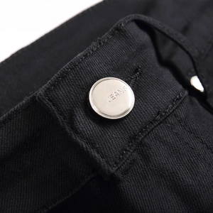 Close-up of black denim jeans showing metal button with JEANS engraving and stitching
