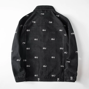 Macro detail of black denim jacket back with white artistic lettering and washed texture