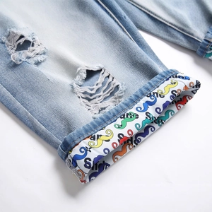 Men's light blue distressed denim shorts featuring ripped details and colorful printed cuffs
