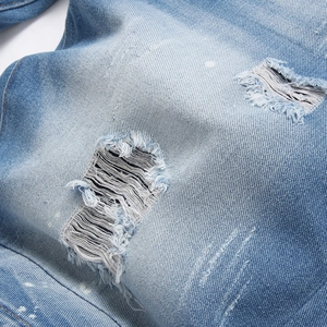 Stylish light blue ripped denim shorts for men with trendy paint splatters and whiskers
