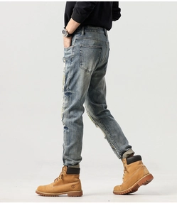 Dettaglio dei jeans azzurri strappati con lavaggio vintage e trama in denim pregiato