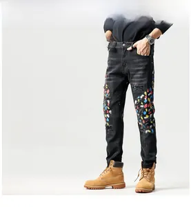 Detail van de zwarte slim fit jeans met kleurrijke verfspatten en stijlvolle scheuren