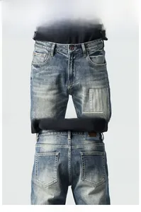 Detail of vintage blue men's jeans featuring distressed whiskers and leather waist patch