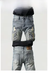 Dettaglio dei jeans blu con ricami personalizzati e finiture vintage effetto usurato